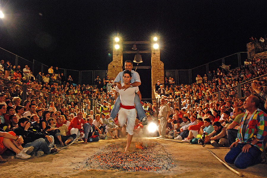 People take part in a fire walking ritual in front of a crowd of people.